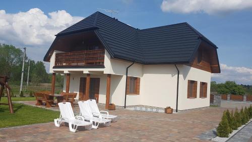 比亚沃维耶扎Apartamenty Białowieża的一座带白色椅子的黑色屋顶房子
