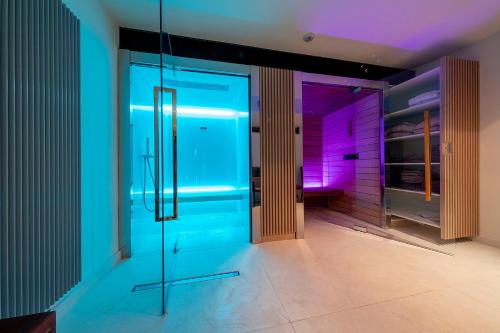 波兹南伊隆酒店的一间设有玻璃门的房间,配有紫色和蓝色的灯光