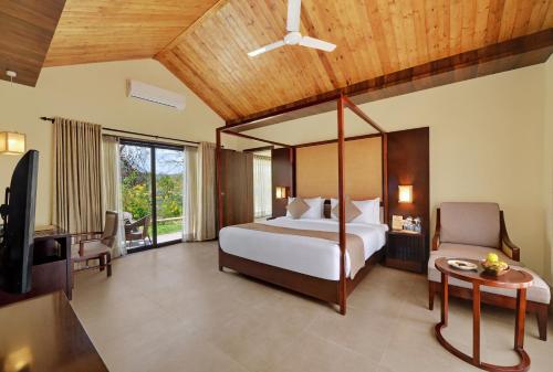 VijayanagarThe Fern Sattva Resort - Polo Forest的一间卧室配有一张床、一张桌子和一台电视。