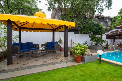 罗纳瓦拉EL Lodge by StayVista - Pool, lawn, and a charming gazebo for your perfect getaway的一个带黄色遮阳伞和游泳池的庭院