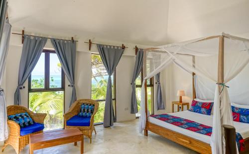 布韦朱Indigo Beach Zanzibar的一间卧室配有一张天蓬床和两把椅子