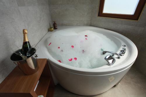 巴尼亚卢卡Provence rooms的旁边配有1个带1瓶香槟的浴缸。