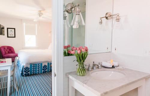 五月岬郡星辰宾馆的浴室设有水槽和粉红色郁金香花瓶