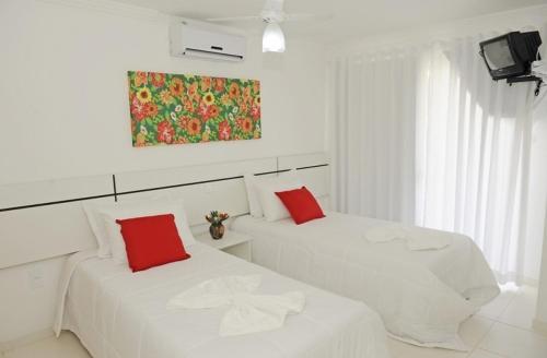 塞古罗港Residencial Mont Sião - Tonziro的白色客房内的两张白色床和红色枕头