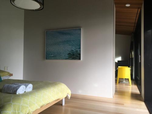 热水海滩Hot Water Beach Bure Wai的卧室配有一张床,墙上挂着一幅画
