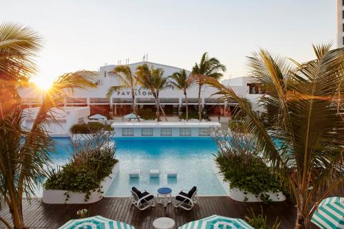 汤斯维尔城市度假酒店 - 赌场的酒店设有带椅子和棕榈树的游泳池