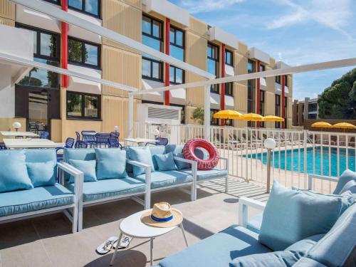 圣罗兰度瓦ibis Styles Nice Cap 3000 Aéroport的酒店庭院设有蓝色的沙发和游泳池