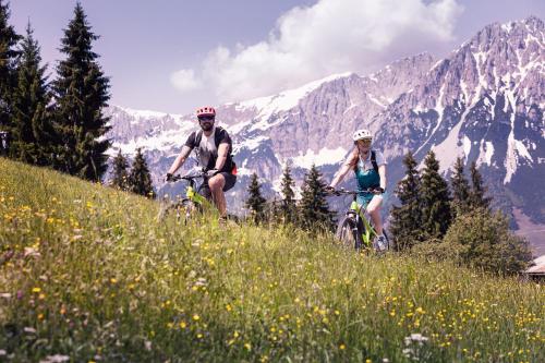 埃尔毛Tirol Lodge的两人骑车在山丘上骑,背景是山丘