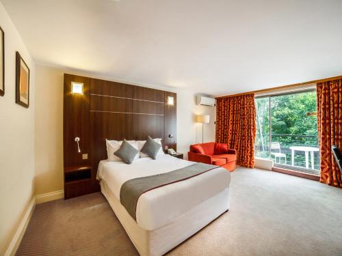 赖盖特The Bridge House Hotel的酒店客房设有一张大床和一张红色椅子。
