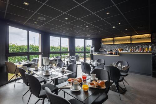 圣雅克德拉朗德Hotel L'Ortega Rennes Aéroport的一间带桌椅的餐厅和一间酒吧