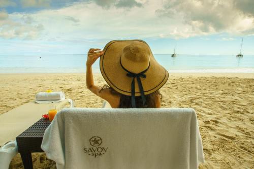 博瓦隆萨沃伊塞舌尔度假村的戴帽子坐在海滩上的人