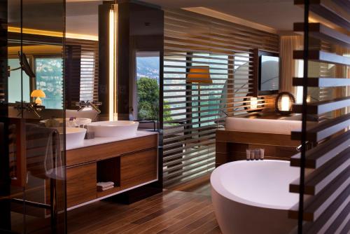 卢加诺卢加诺风景酒店的一间带两个盥洗盆、浴缸和卫生间的浴室