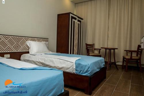 拉斯巴尔El Mena Beach的酒店客房带两张床和一张桌子以及椅子。