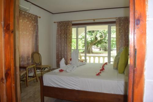 拉迪格岛绿竹小屋旅馆的一间卧室配有一张带白色床单的床和一扇窗户。