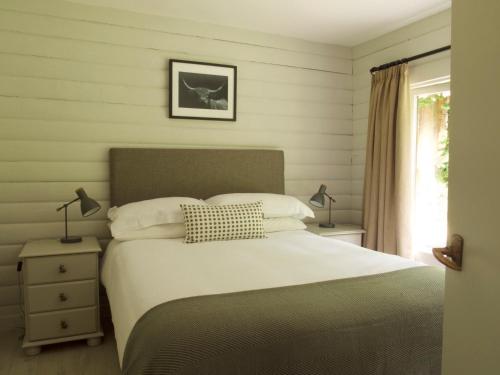 斯特拉西尔Mews Cottage Ardoch Lodge Strathyre的一间卧室配有一张床、两盏灯和一个窗户。