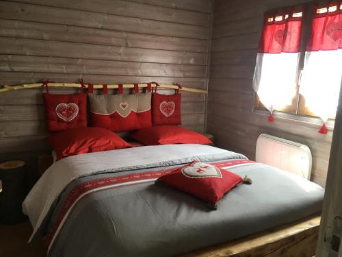 圣迪耶Le chalet des Cambuses的宿舍间内的一张床位,上面有红色枕头