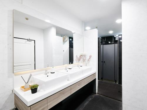 新加坡BEAT. Sports Hostel的白色的浴室设有两个盥洗盆和镜子