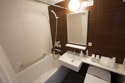 静冈奎斯特清水酒店的浴室配有盥洗盆、卫生间和浴缸。