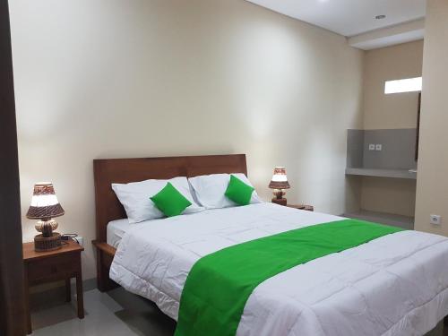 乌布Gusti Room的一间卧室配有一张带两盏灯的绿色和白色的床。