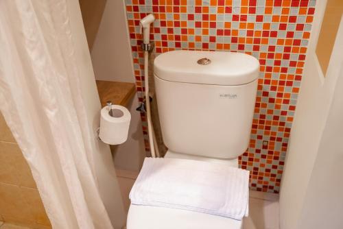 雅加达塞纳扬拉格林套房酒店的浴室配有带浴帘的卫生间