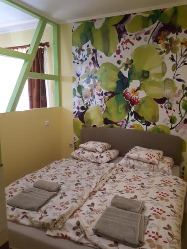 久洛Rozmaring Apartmanok的一间卧室配有带枕头的床铺和花卉墙