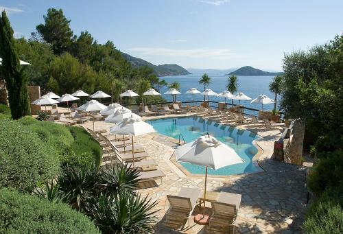 波尔图·埃尔科莱佩里卡诺酒店的游泳池配有椅子和遮阳伞,水中
