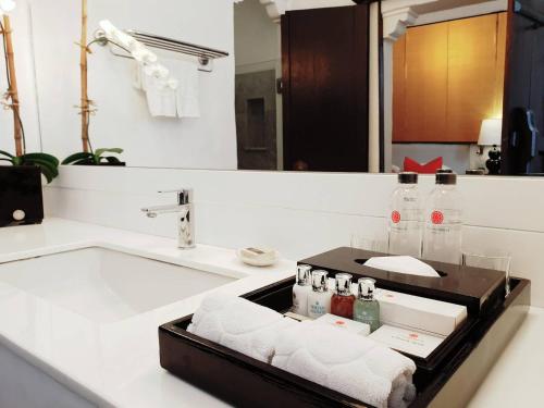 清迈Rachamankha Hotel的浴室设有水槽、瓶子和毛巾