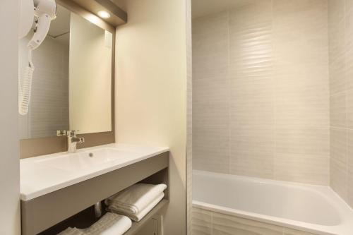 滨海卡瓦莱尔Résidence Prestige Odalys Les Canissons的白色的浴室设有水槽和浴缸。