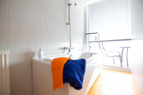 派尔努City center apartment Aida的白色浴缸配有橙色和蓝色毛巾