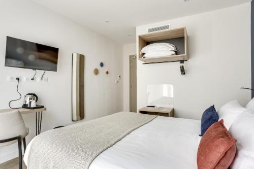 库尔布瓦Hotel Courseine的一间白色卧室,配有床和电视