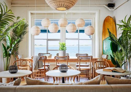 新肖雷汉姆Block Island Beach House的餐厅设有桌椅和大窗户。