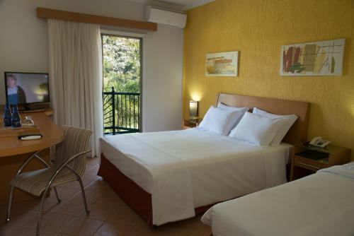 阿瓜斯迪林多亚奥斯卡生态度假酒店的酒店客房设有两张床、一张书桌和一个窗户。