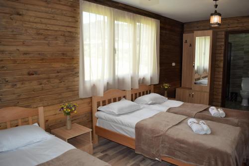 卡兹贝吉Gergeti Woods的卧室设有两张床,配有木墙和窗户。