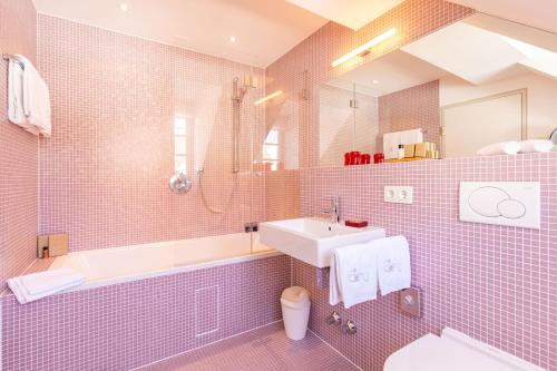 埃夫林根基兴Traube Blansingen的粉红色的瓷砖浴室设有水槽和浴缸