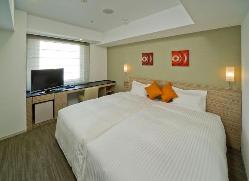 横滨横滨户冢索特图斯弗雷撒酒店的卧室配有一张白色大床和一台平面电视。