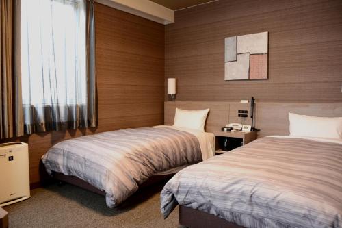 上田市上田站前皇家酒店的酒店客房设有两张床和窗户。