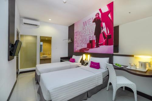 雅加达普鲁特村最爱酒店的酒店客房设有两张床和粉红色的墙壁。