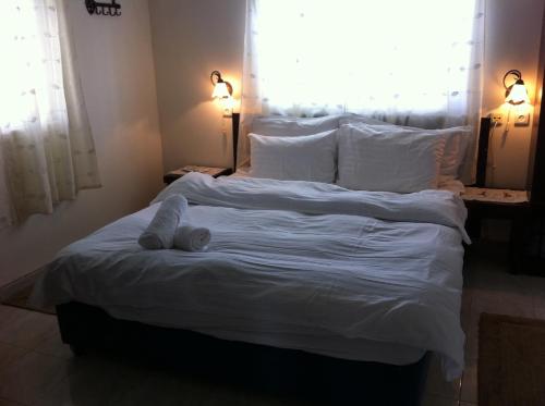 Arbel阿贝尔沙维特家庭宾馆的一张铺有白色床单的床,上面有一只填充物