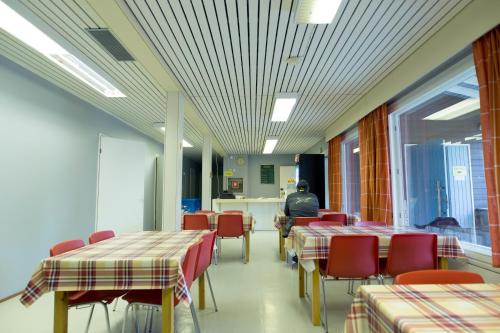 SaariharjuNikkilän Elämyskylä的一间食堂,配有桌椅,还有一位坐在桌子旁的人