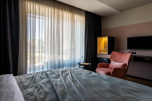 利耶帕亚Maestro Design Hotel的酒店客房配有一张床、一把椅子和一台电视。