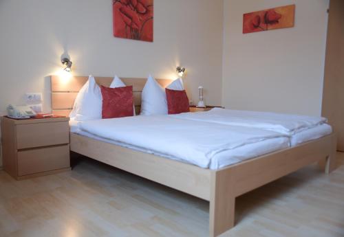 Schwarzenberg am BohmerwaldHotel Bergkristall的一间卧室配有带白色床单和红色枕头的床。
