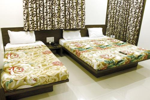 舍地Hotel Shradha Saburi Palace的两张睡床彼此相邻,位于一个房间里