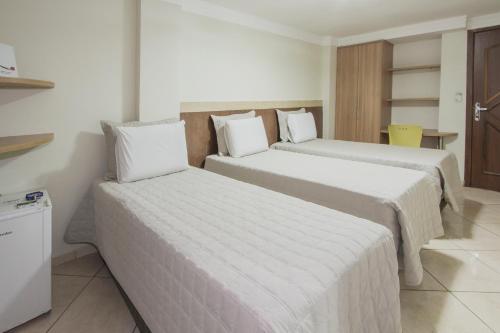 巴西利亚阿尔法广场酒店 的酒店客房,配有两张带白色床单的床