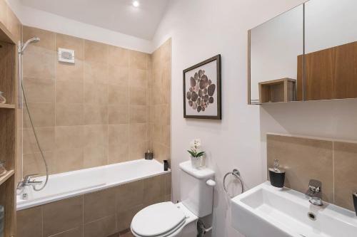 伦敦Beautiful West London House的浴室配有卫生间、浴缸和水槽。