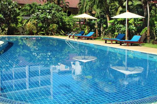 芭东海滩Patong Palace Hotel - SHA Extra Plus的一个带两把椅子和遮阳伞的游泳池