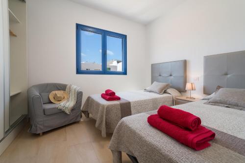 塞博河畔卡莱塔CALIMAS的一间卧室设有两张床、一把椅子和一个窗户。