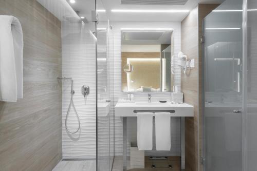 帕尔马诺瓦Elba Sunset Mallorca Thalasso Spa的浴室配有盥洗盆和带镜子的淋浴