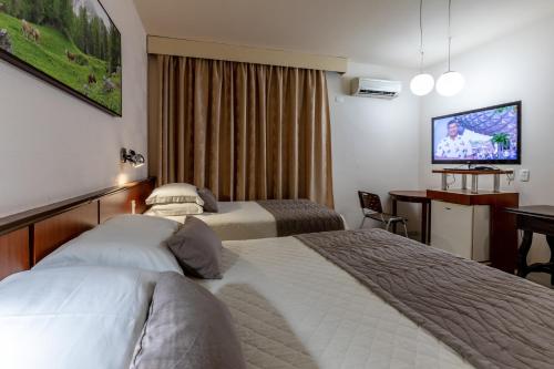 伊瓜苏Aguas do Iguaçu Hotel Centro的酒店客房设有两张床和一台平面电视。