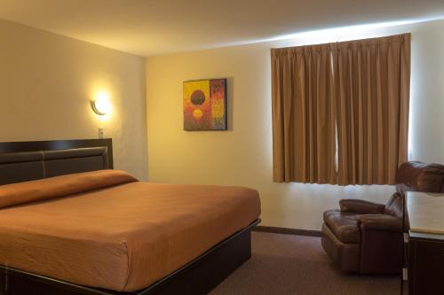 坦皮科BONITTO INN® Tampico Aeropuerto的配有一张床和一把椅子的酒店客房