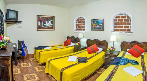 危地马拉安地瓜Posada San Vicente by AHS的配有黄色床单的客房内的两张床